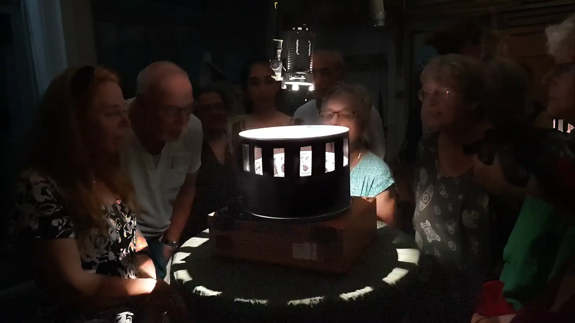 Menschen versammeln sich um ein Zoetrop, um sich eine Animation anzusehen