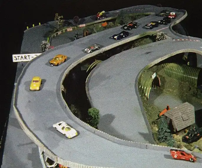 Film still from the stop-motion film Competition Without Winners. The image shows matchbox cars on a model race track.