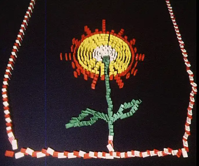 Film still from the stop-motion film DOMINO-PLAY. The image shows domino tiles arranged in the shape of a flower.