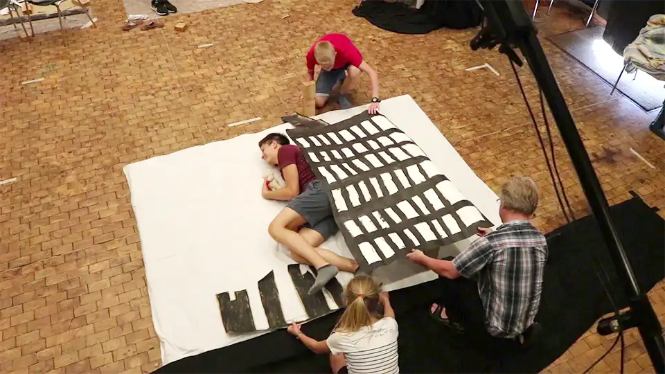 Pixilation-Workshop-2010-film-shoot-birds-eye-view-960x540 Overhead view of a pixilation film shoot: Participants animate a large paper backdrop around a performer lying on the floor.