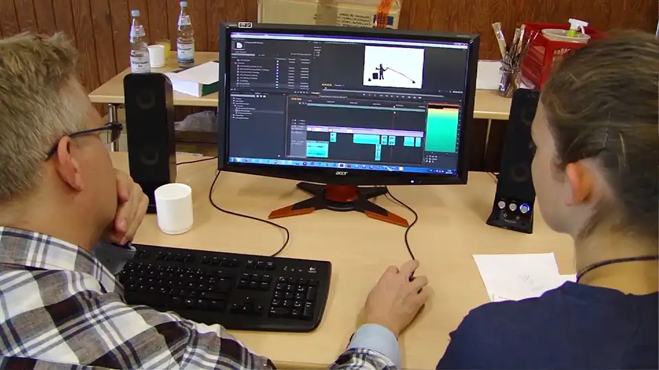 Thomas Stellmach und ein Teilnehmer bearbeiten einen Animationsfilm am Computer mit Schnittsoftware.